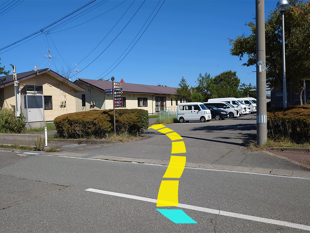 写真:直進し、ほのぼの苑、正和会本部の建物を超えた進入路を右折し、すぐ緑のフェンスの前を左折します。