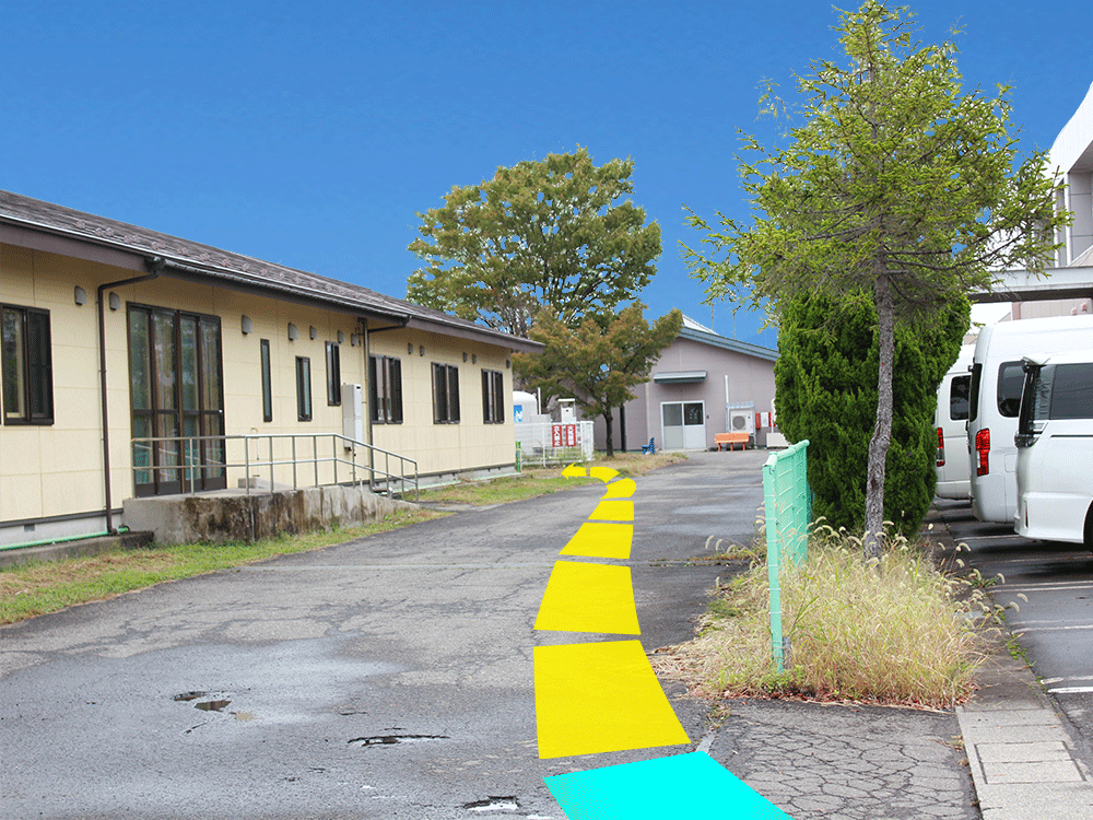 写真:左手の建物沿いに直進し建物を超えたら左折します。
